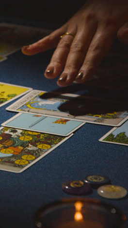 Vertical-Video-Close-Up-Of-Woman-Giving-Tarot-Card-Reading-On-Candlelit-Table-3